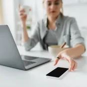 Vrouw grijpt naar smartphone achter bureau